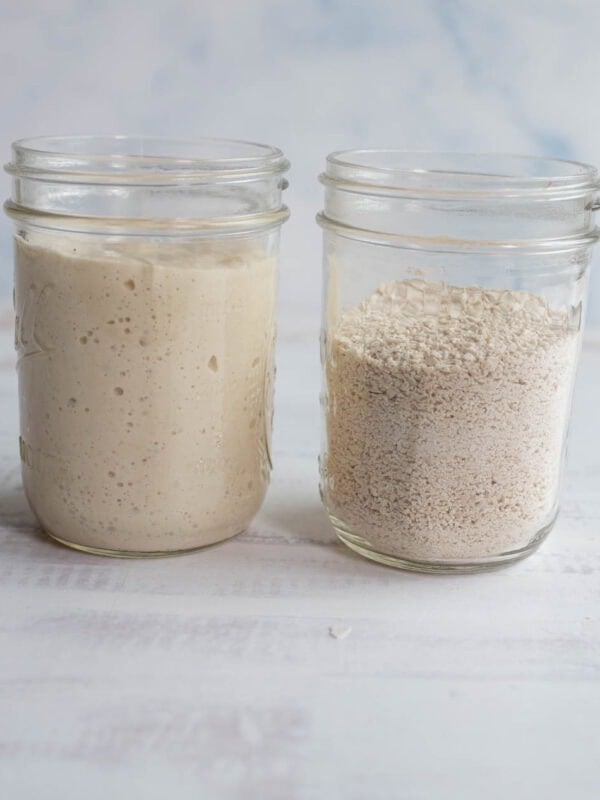 a jar of active bubbly sourdough starter sitting next to a jar of dehydrated starter crumbs.