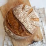 round loaf of sourdough rye bread on brown wooden board.