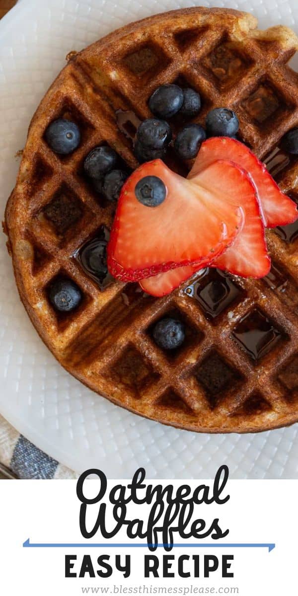 A round waffle topped with fresh blueberries and sliced strawberries is on a white plate. A portion of the plate sits atop a striped cloth. The text below reads, Oatmeal Waffles: Easy Recipe with a website link.