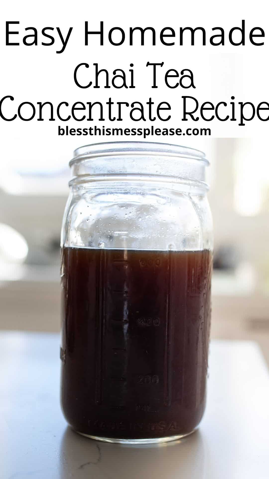 A clear glass jar filled with dark brown chai tea concentrate. The text above reads, Easy Homemade Chai Tea Concentrate Recipe with a website URL. The background is softly blurred.