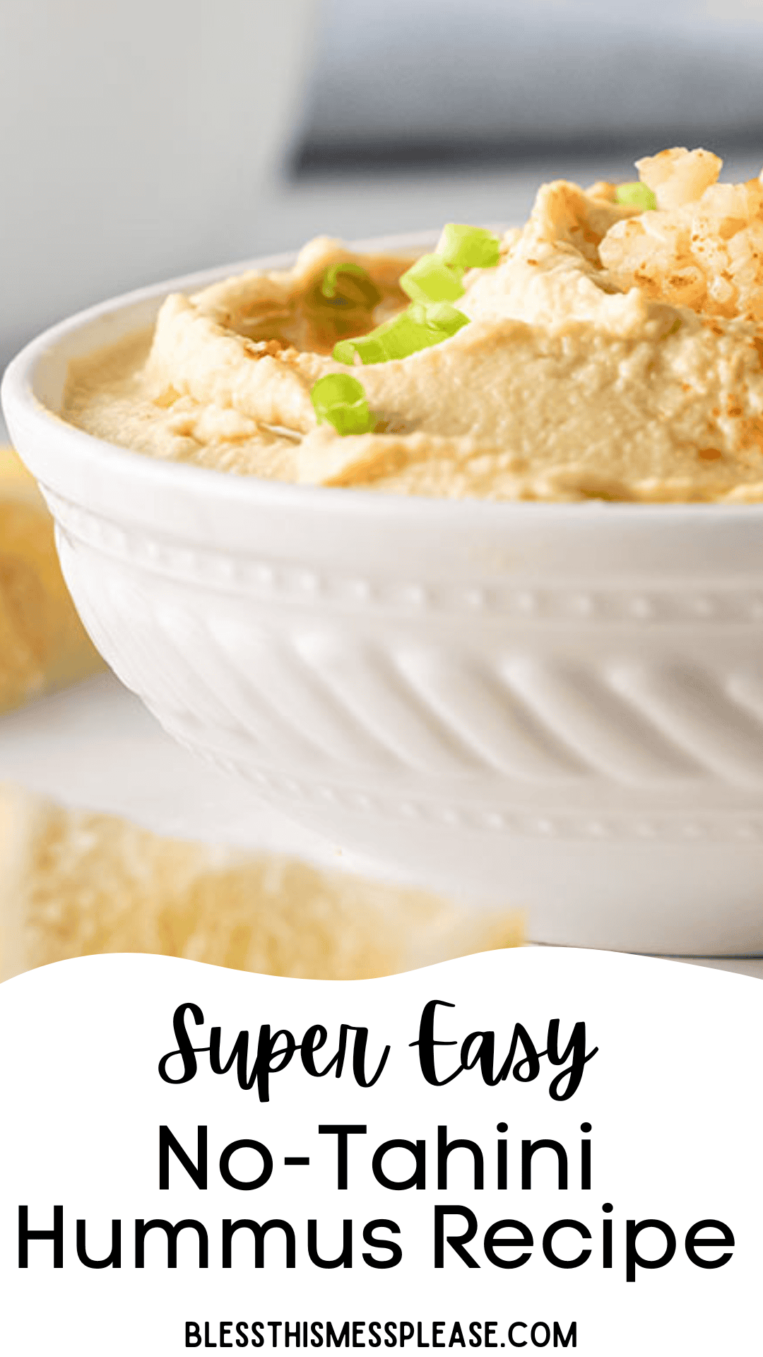 A close-up of a white bowl filled with creamy garlic hummus, garnished with chopped green onions and a sprinkle of spices. The text below reads Super Easy Garlic Hummus Recipe Without Tahini.