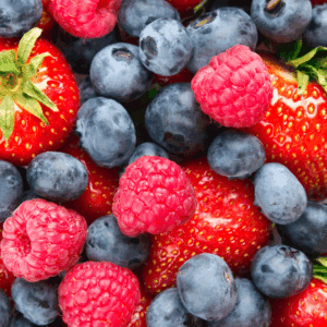 A close-up view of fresh strawberries, blueberries, and raspberries, showing their vibrant red and blue colors. The berries are mixed together, filling the entire frame—perfect for learning how to preserve berries at their freshest.