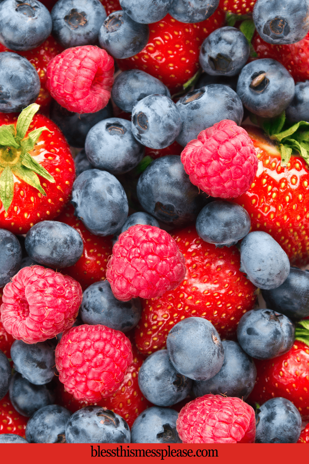 A close-up of fresh strawberries, blueberries, and raspberries piled together, showing their vibrant red and blue colors and juicy textures. The website blessthismessplease.com appears at the bottom.