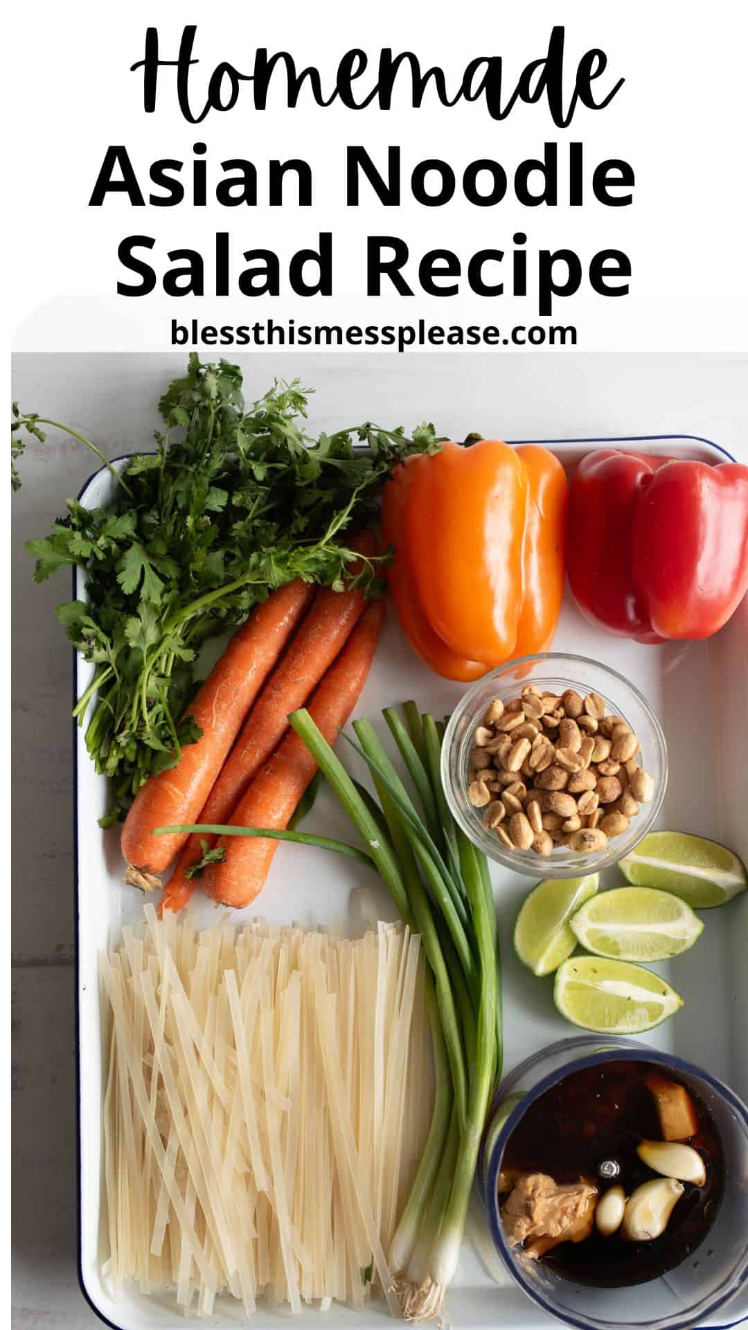 Overhead view of fresh ingredients for Asian noodle salad: carrots, cilantro, orange and red bell peppers, green onions, peanuts, lime wedges, rice noodles, and a bowl of sauce on a white tray.