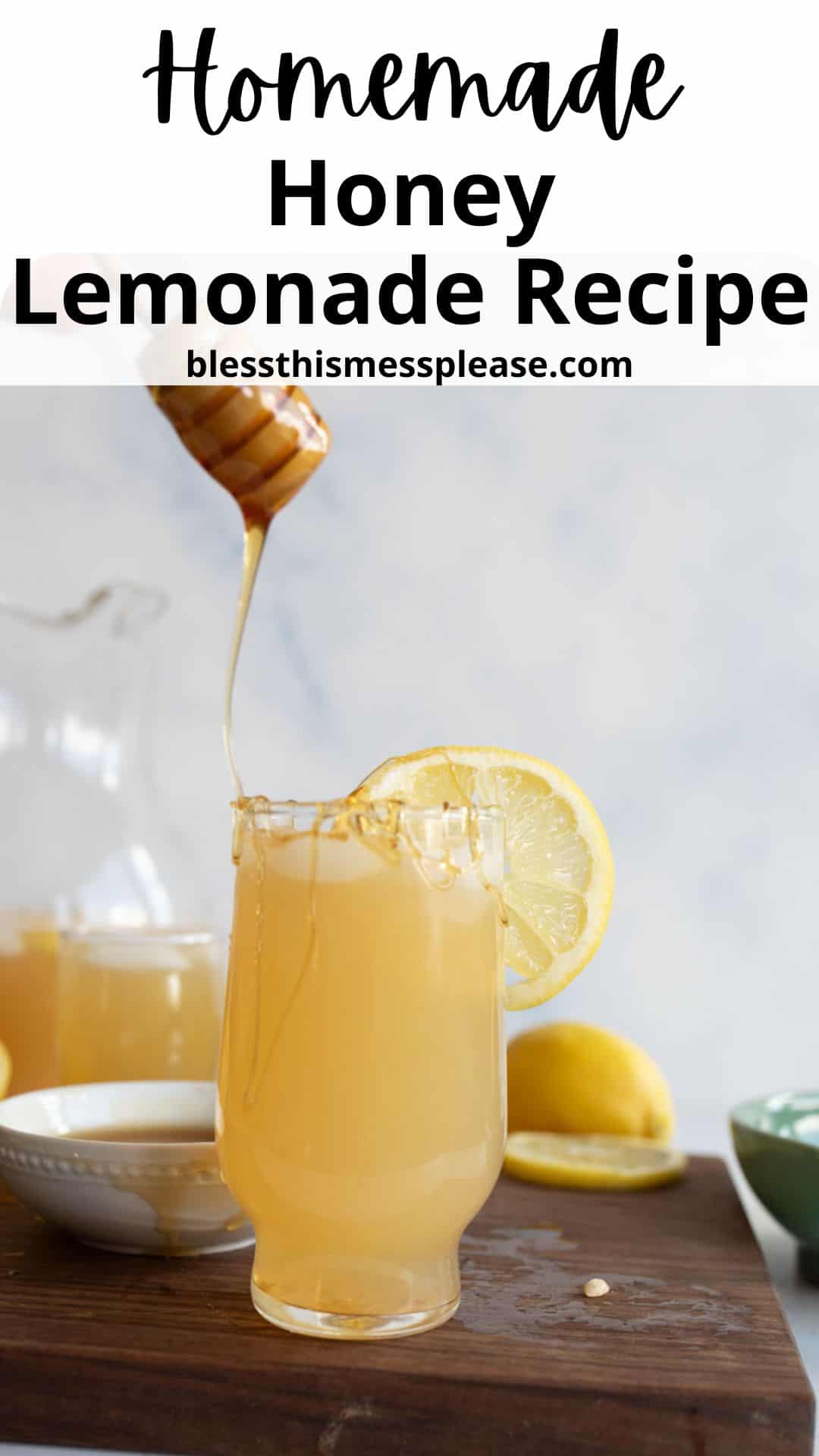 A glass of honey lemonade garnished with a lemon slice on a wooden surface, with honey being drizzled in, a pitcher, lemon halves, and a small bowl in the background. Text reads: Homemade Honey Lemonade Recipe.