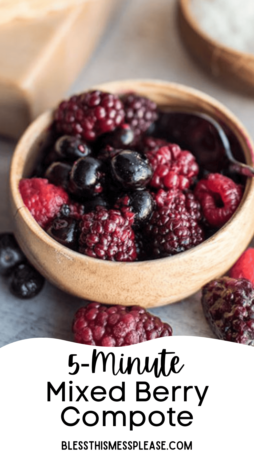 A wooden bowl filled with mixed berries, perfect for a homemade berry compote, sits on a gray surface. Text below reads: 5-Minute Mixed Berry Compote blessthismessplease.com.