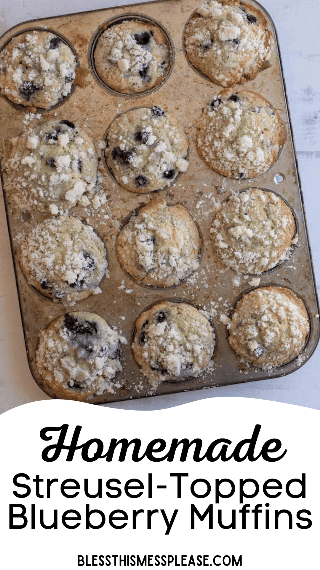A muffin tin filled with twelve homemade blueberry streusel muffins, each topped with a crumbly streusel, sits on a white surface. Text at the bottom reads Homemade Streusel-Topped Blueberry Muffins.