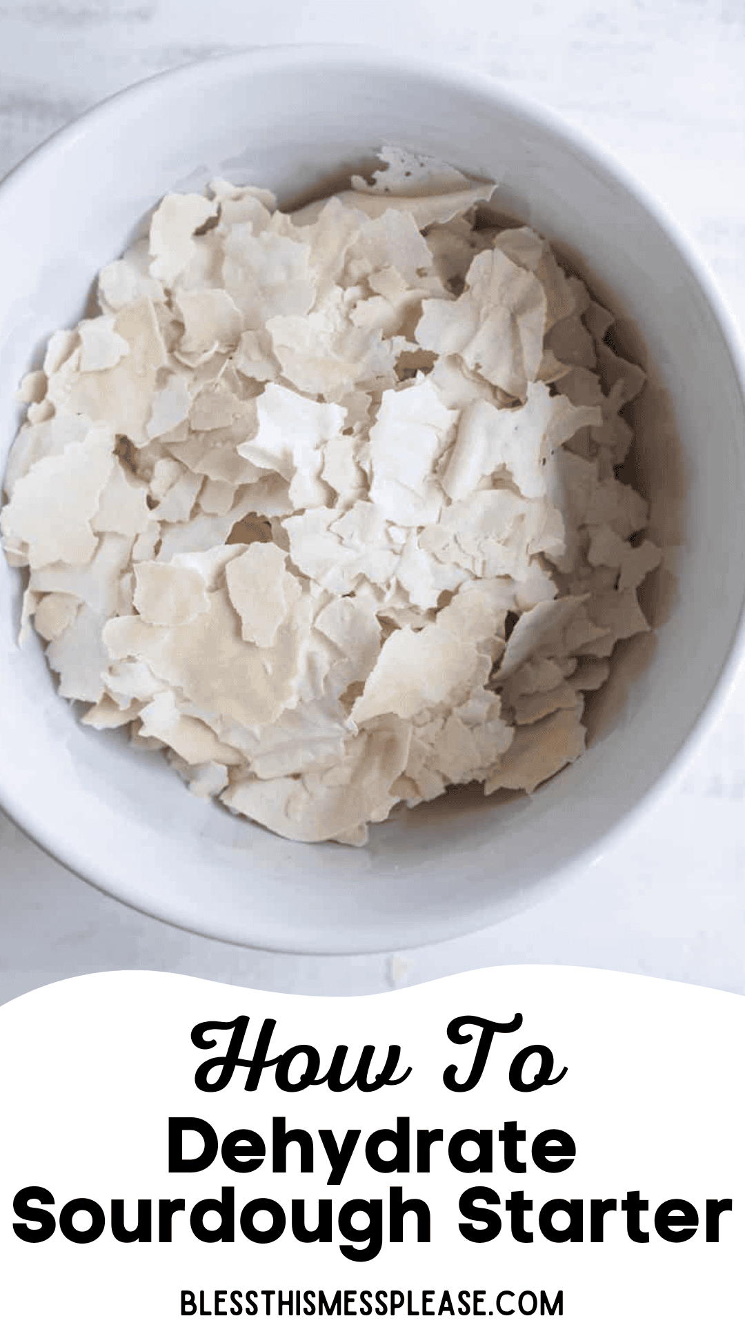 A white bowl filled with dried, flaky pieces of sourdough starter shows how to dehydrate sourdough starter. Text below the bowl reads, How To Dehydrate Sourdough Starter with blessthismessplease.com at the bottom.