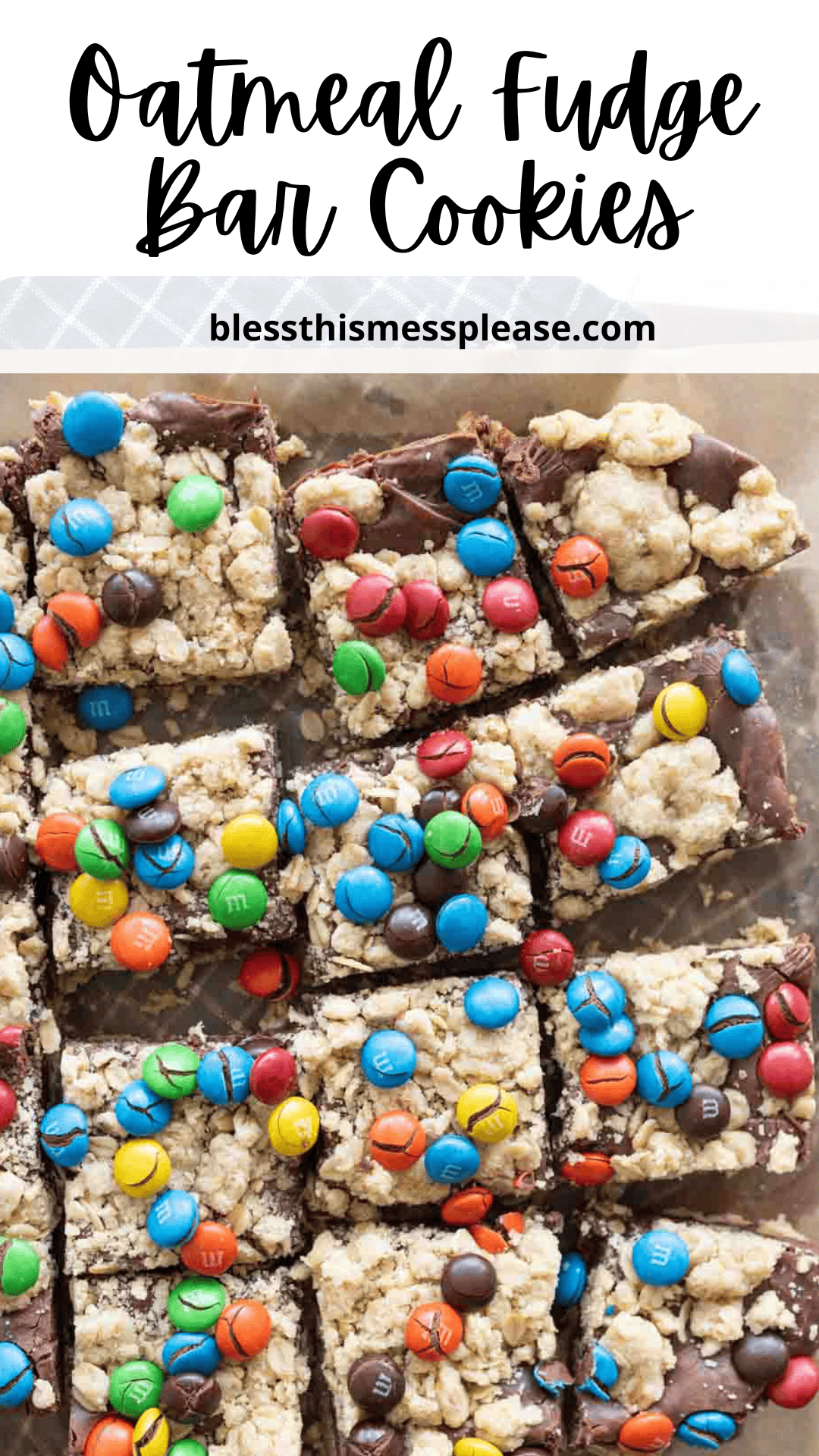 Top-down view of oatmeal fudge bars topped with colorful M&M candies, cut into squares and arranged on a tray. Text at the top reads Oatmeal Fudge Bar Cookies and blessthismessplease.com.