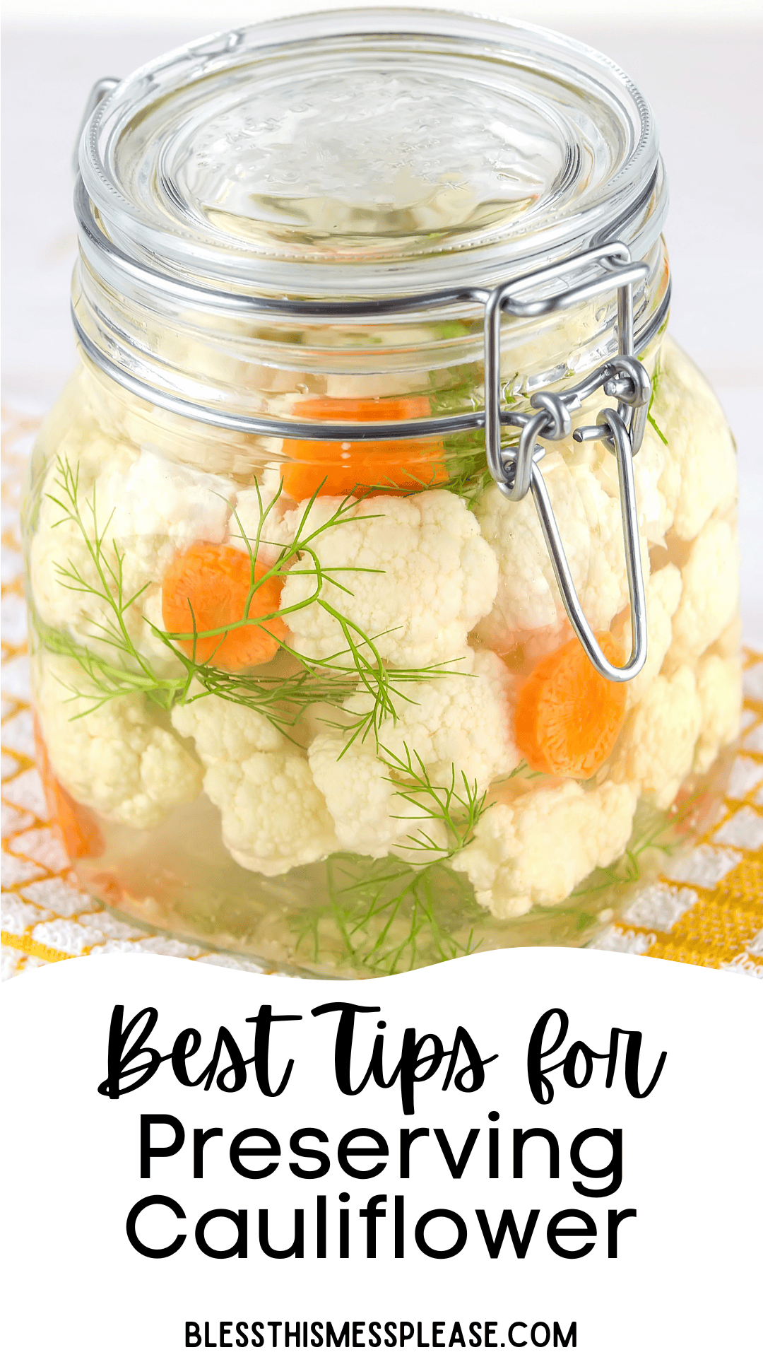 A glass jar filled with cauliflower florets, carrot slices, and dill sprigs sits on a yellow checkered cloth. Text below reads: Best Tips for how to preserve cauliflower BLESSTHISMESSPLEASE.COM.