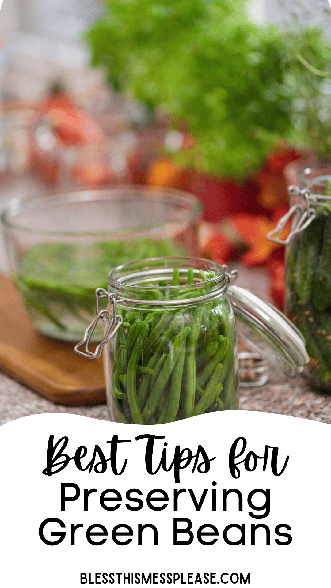 A glass jar filled with fresh green beans sits on a kitchen counter, surrounded by more jars and vegetables. Text reads, Best Tips on How to Preserve Green Beans. blessthismessplease.com.
