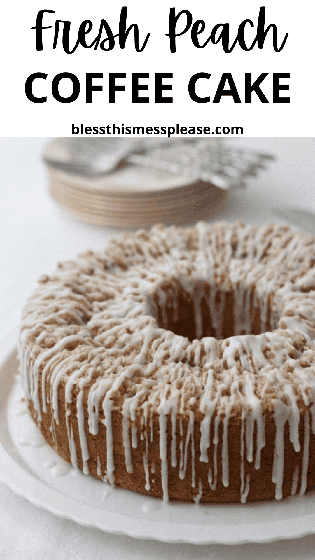 A round peach coffee cake with crumb topping and drizzled white icing sits on a white plate. Stacked plates and napkins are blurred in the background. Text above reads: Fresh peach coffee cake.
