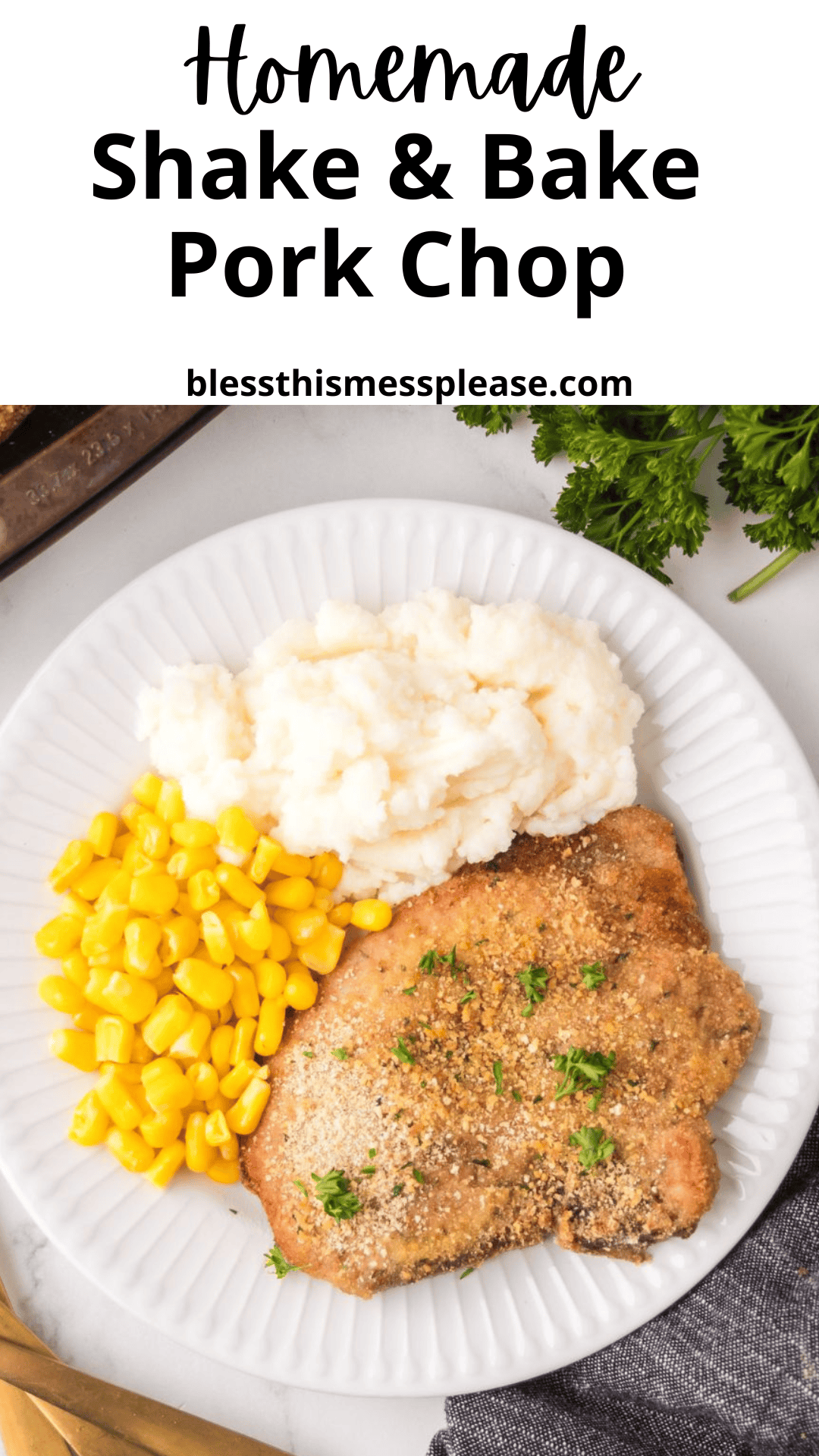 A plate with homemade shake and bake pork chops topped with herbs, served alongside mashed potatoes and yellow corn. The plate sits on a white surface near gold utensils, a napkin, and fresh parsley.
