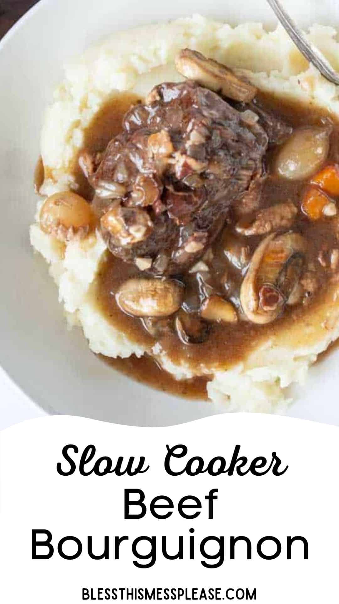 A serving of slow cooker beef bourguignon with mushrooms and carrots in a rich brown sauce, served over mashed potatoes on a white plate. Text reads, Slow Cooker Beef Bourguignon, blessthismessplease.com.