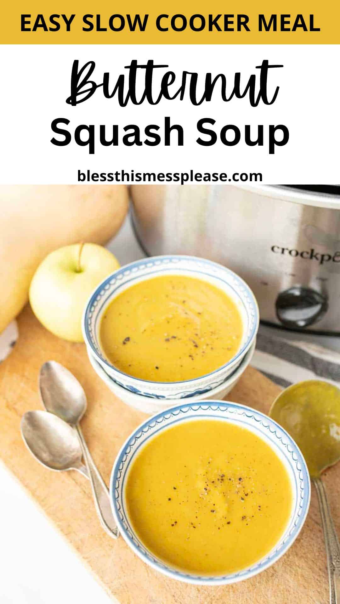 Two bowls of slow cooker butternut squash soup sit on a wooden surface with spoons, a yellow apple, and a slow cooker in the background—enjoy this easy and comforting meal perfect for any night.