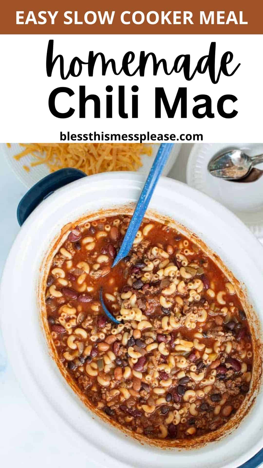 A white slow cooker filled with slow cooker chili mac, featuring macaroni noodles, beans, and ground meat in tomato sauce. A blue spoon is in the pot, with shredded cheese and a spoon nearby. Text above reads Easy Slow Cooker Meal Homemade Chili Mac.