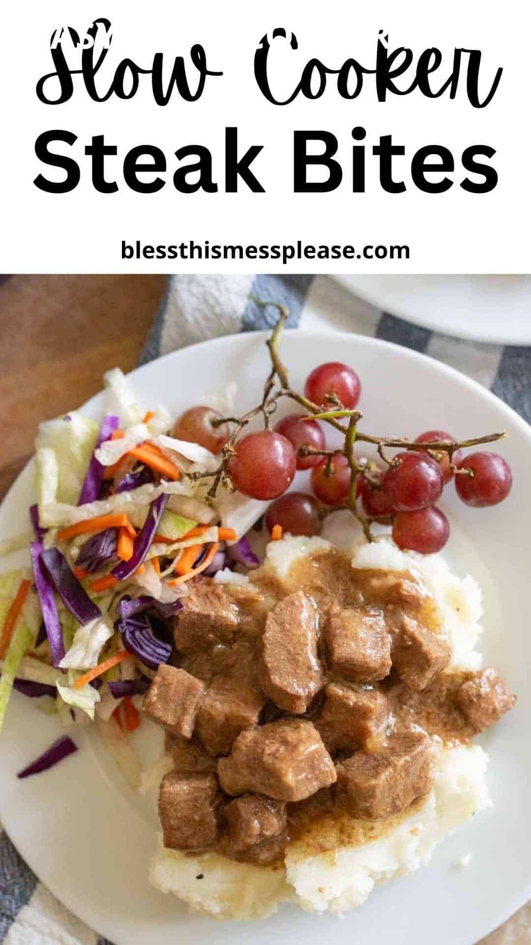 A plate of savory slow cooker steak bites in rich gravy served over mashed potatoes, paired with shredded coleslaw and a bunch of red grapes. The top text reads Slow Cooker Steak Bites.