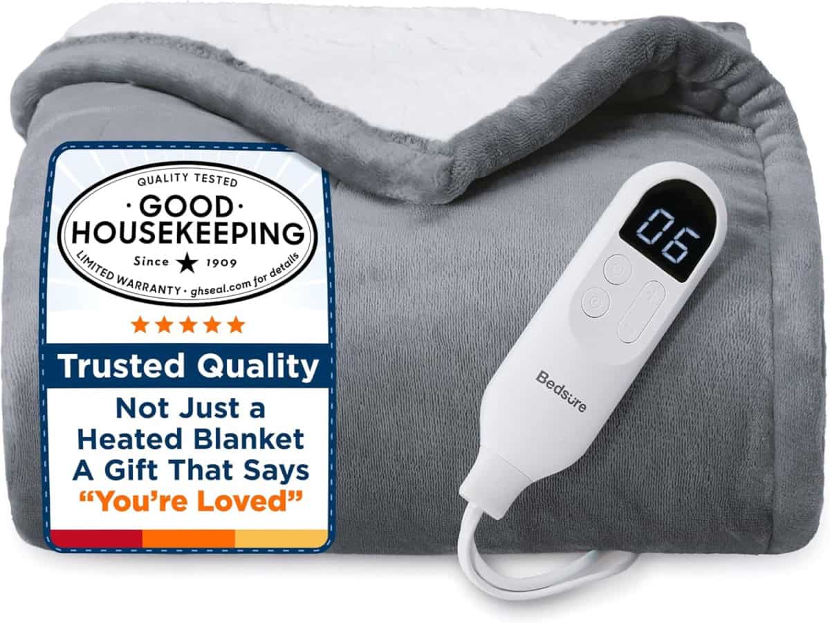 A folded gray heated blanket with a white controller displaying 06, next to a label that reads: Good Housekeeping, Trusted Quality, and Not Just a Heated Blanket, A Gift That Says You’re Loved.