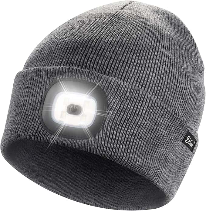 A gray knit beanie hat with a built-in bright LED headlamp on the front, shown illuminated. A small black label is sewn onto the cuff of the beanie.