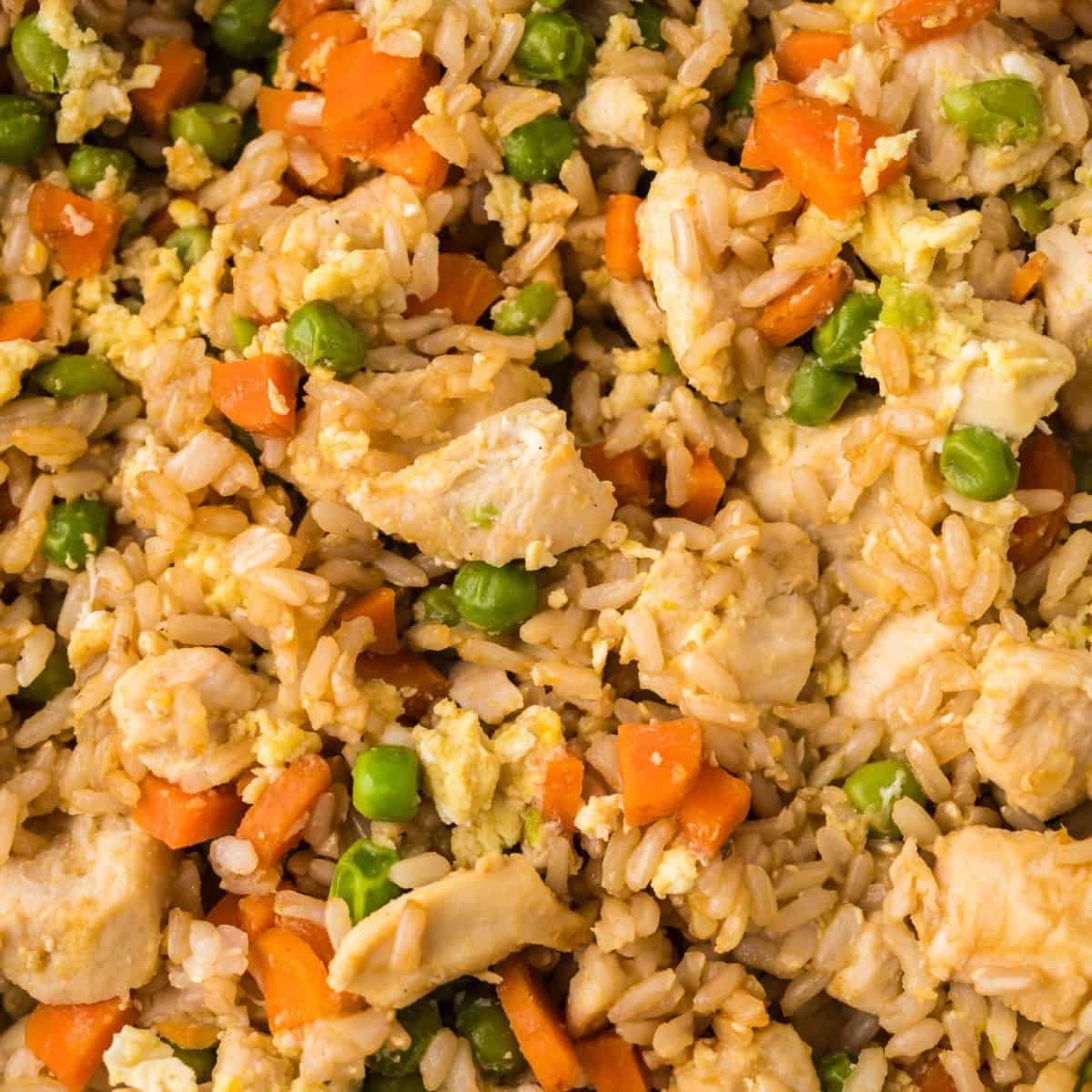 Close-up of chicken fried rice, showing chunks of chicken, diced carrots, green peas, scrambled egg, and rice all mixed together—perfect inspiration for making chicken fried rice at home.