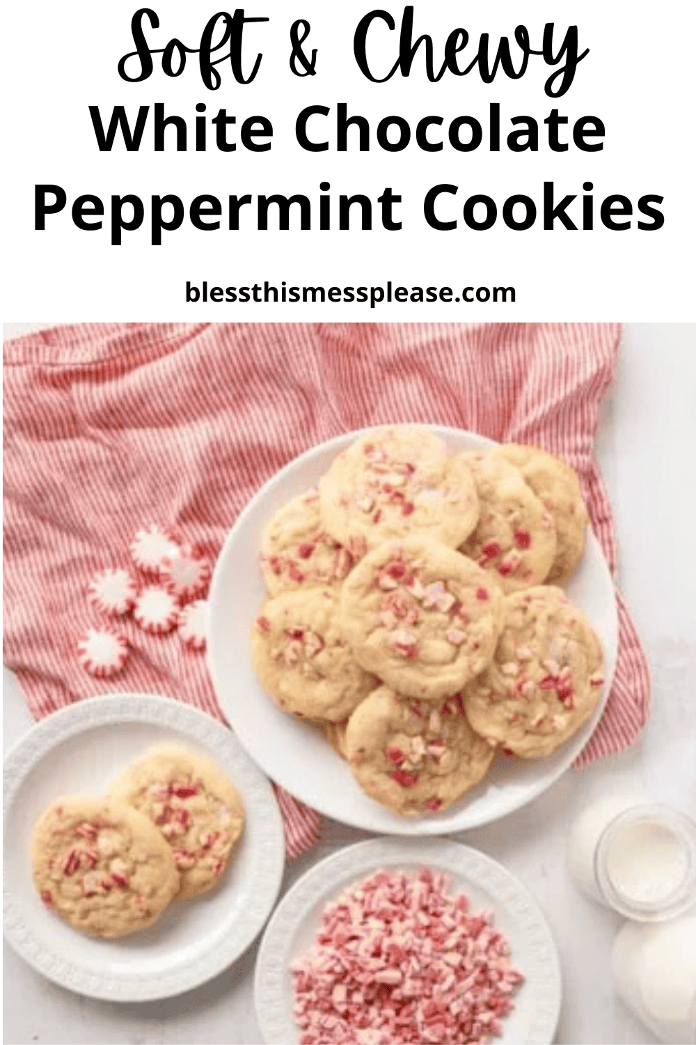 A plate of white chocolate peppermint cookies rests on a pink striped cloth, surrounded by whole peppermints, a bowl of crushed peppermints, a glass of milk, and more white chocolate peppermint cookies on smaller plates.