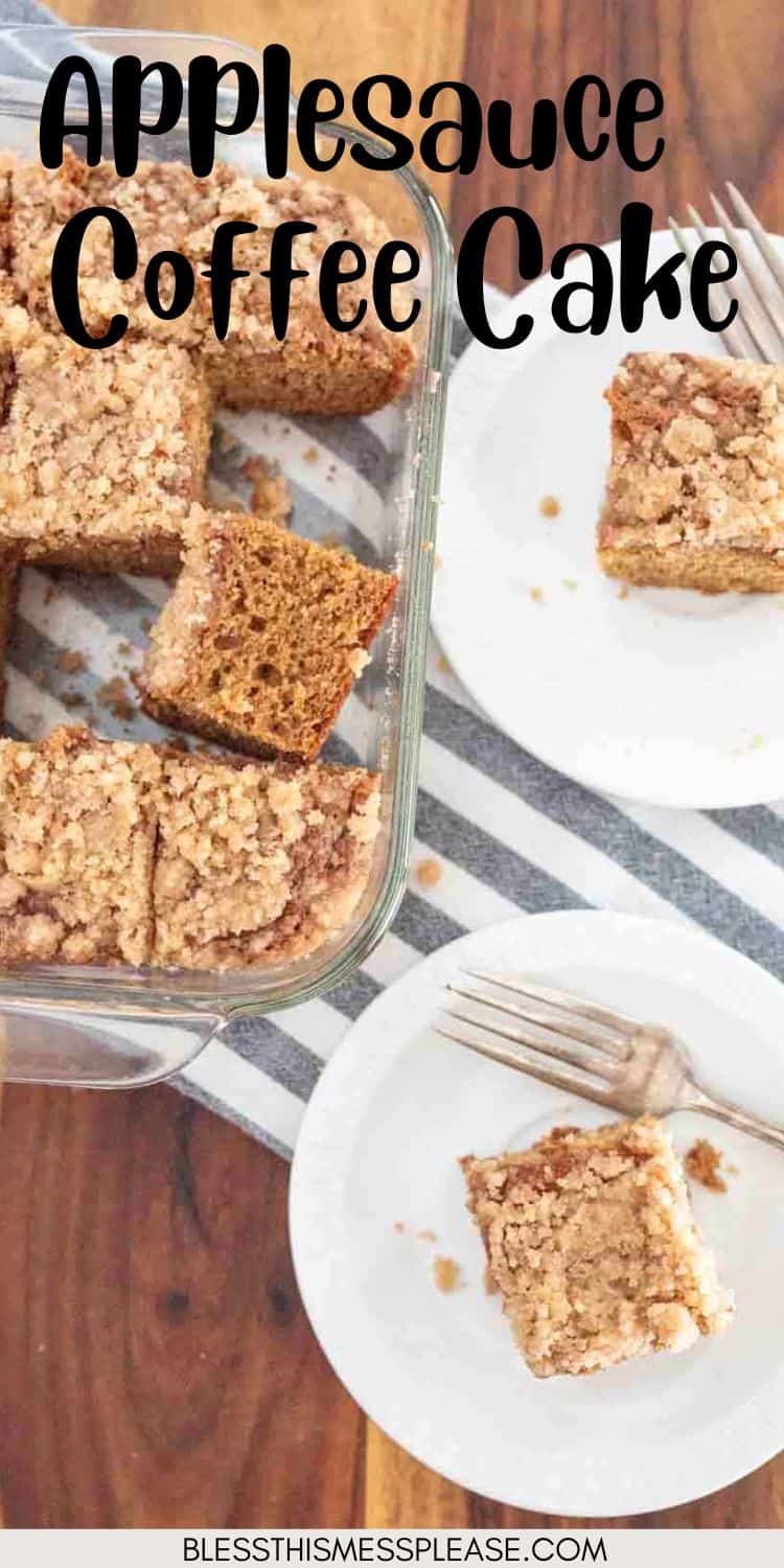 A glass baking dish with slices of applesauce coffee cake sits next to two white plates, each holding a piece of this moist applesauce coffee cake and a fork, on a wooden table with a striped cloth.